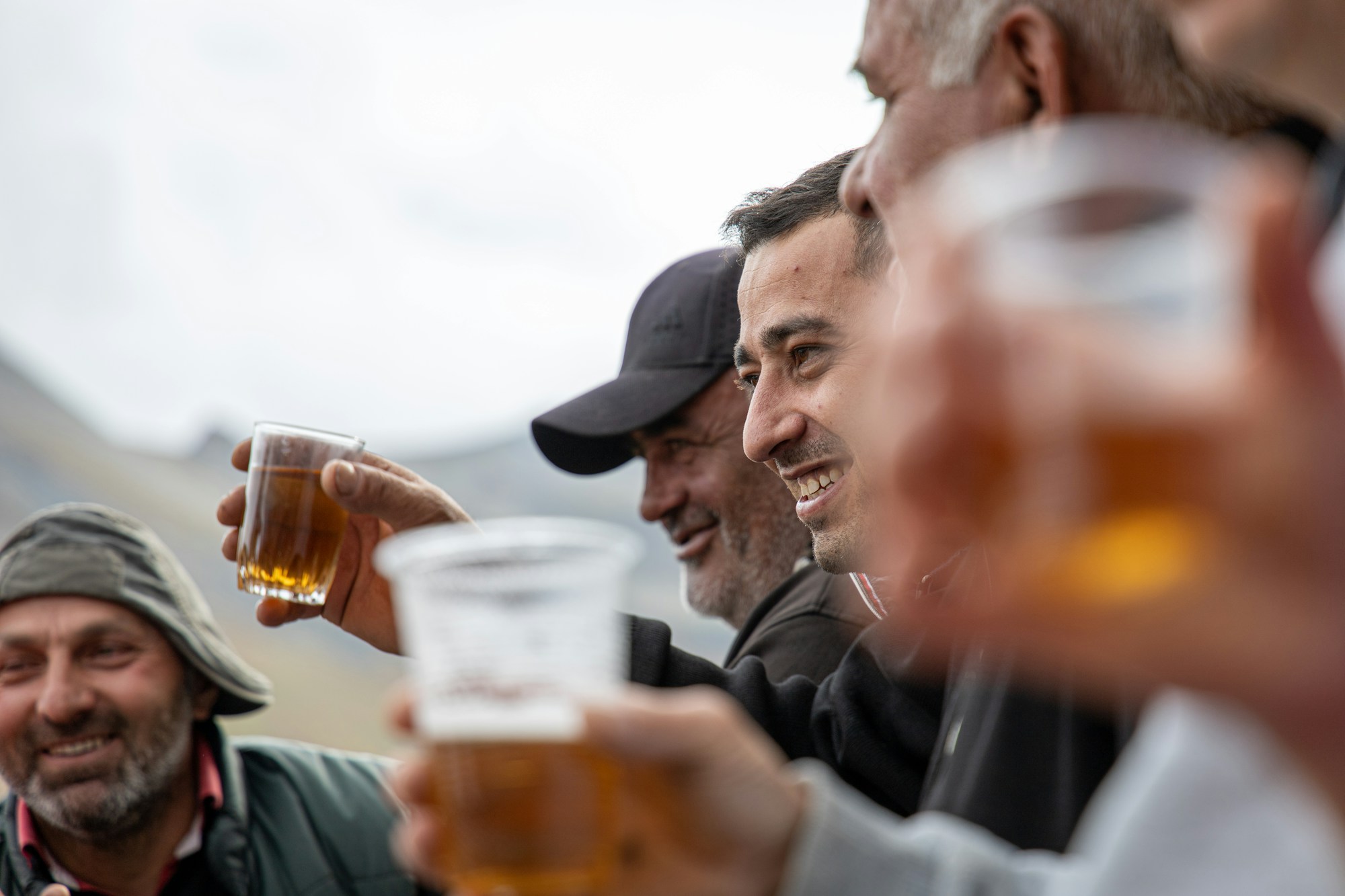 A group of adult men smiling and raising glasses of beer together