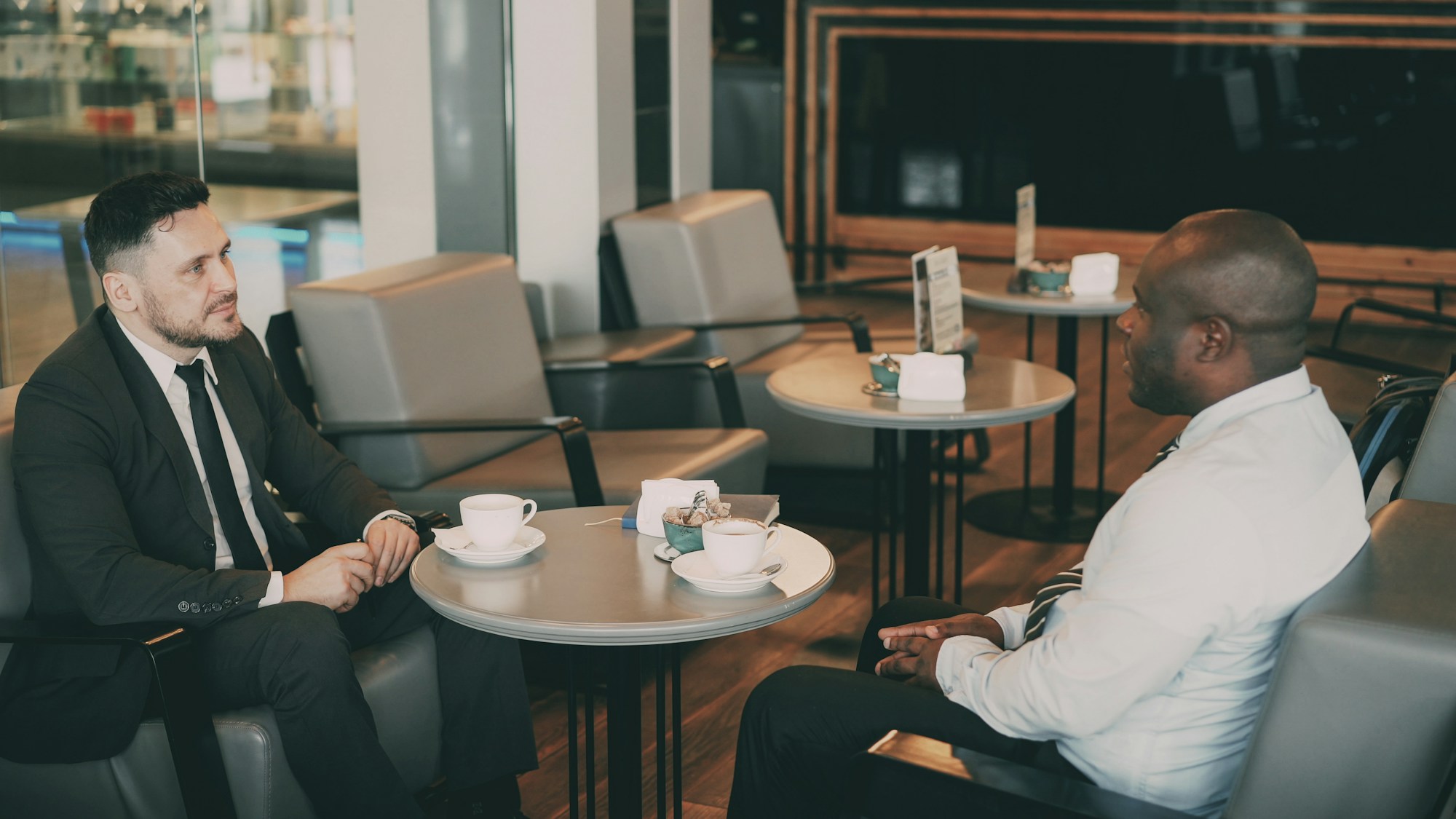 Two men talking over coffee at a cafe table
